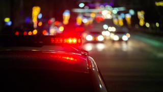 Blurred view of city traffic at night with red police car lights flashing in the foreground that symbolizes a Texas drunk driving accident lawyer.