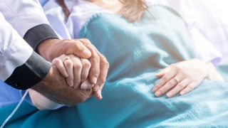 A doctor gently holding a patient’s hand in a hospital bed, showing compassion and support that symbolizes a FTCA birth injury lawyer for military and VA medical malpractice cases.